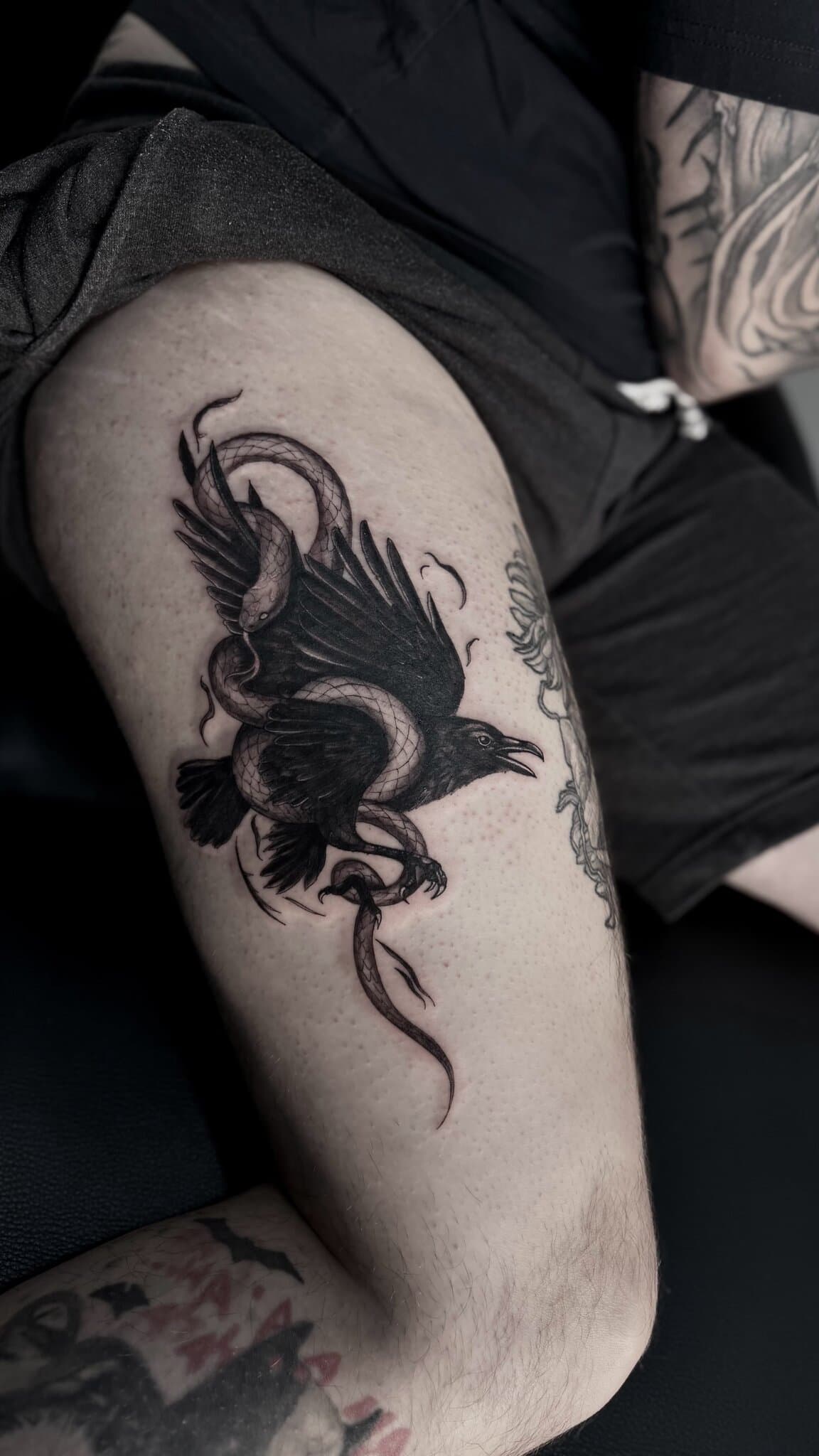 Raven entwined with a serpent, blackwork, thigh — by Stefan Buttigieg