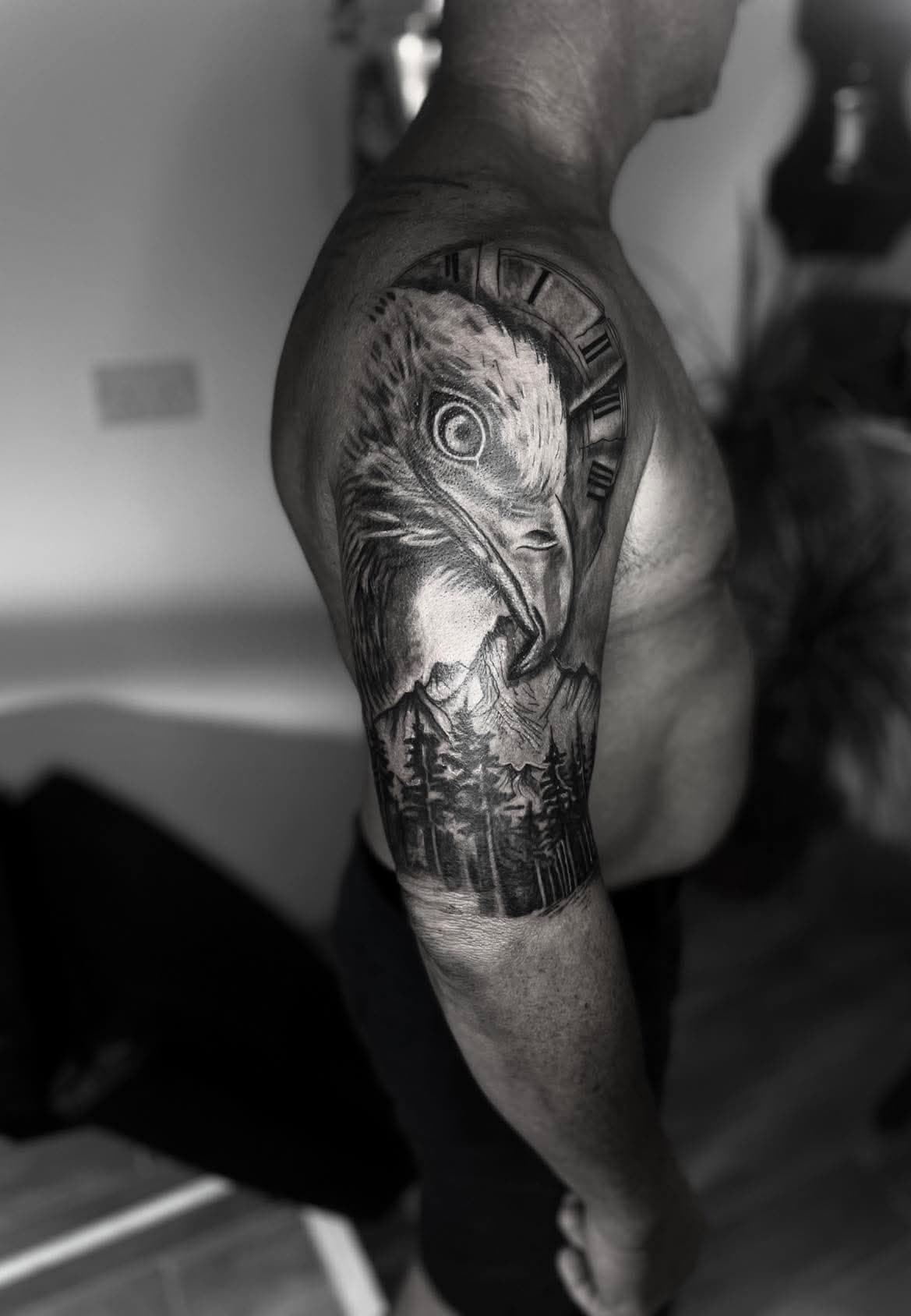 Eagle with a clock face over a pine forest, black-and-grey realism, upper arm — by Stefan Buttigieg at Ink Alley, Żabbar